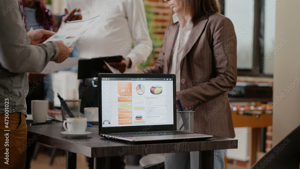 Poster close up of laptop with business charts on desk in startup office. colleagues working together to pl