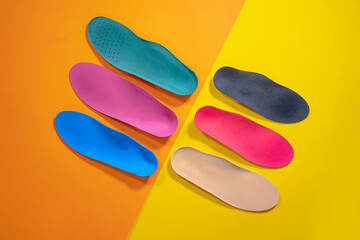 Orthopedic insoles are lined up on a wooden surface. samples of different orthopedic insoles. insoles with a variety of coating. - obrazy, fototapety, plakaty