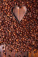Empty Heart shape made inside of coffee beans background. Flat lay. Symbol of Love to coffee. Vertical wooden wallpaper