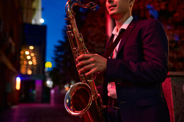 Obraz premium Saxophonist plays the sax on darke street at night