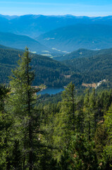 Bergige Landschaft in Österreich.  Blick von einem hochgelegenen Punkt auf  eine Gebirgskette und einem kleinen See im Tal. Sonniger Herbsttag