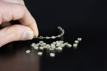 Braces and rubber bands for aligning teeth on a dark background. The orthodontist's hand holds the...