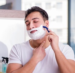 Young handsome man shaving in the morning