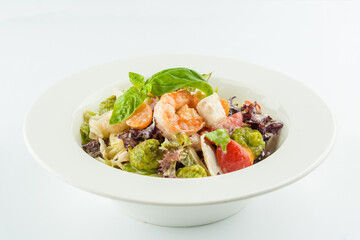 Seafood salad with grilled Shrimp, cherry tomatoes, Tofu cheese, cilantro, lettuce with classic guacamole sauce made of avocado served on square plate. Dish isolated on white background
