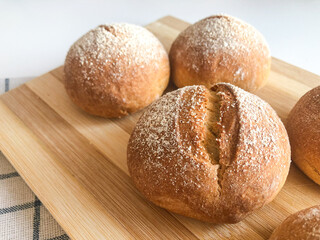 Close up of Traditional mini French wheat bun Petit Pain. Little buns for breakfast served on wooden cutting board with textile kitchen towel on background 
