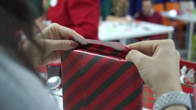 Christmas gift wrapping. The girl's hands are wrapping gifts in red kravtovaya paper. New Year shopping, Christmas discounts