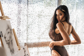 Sexy Asian woman with paintbrush in art gallery - obrazy, fototapety, plakaty