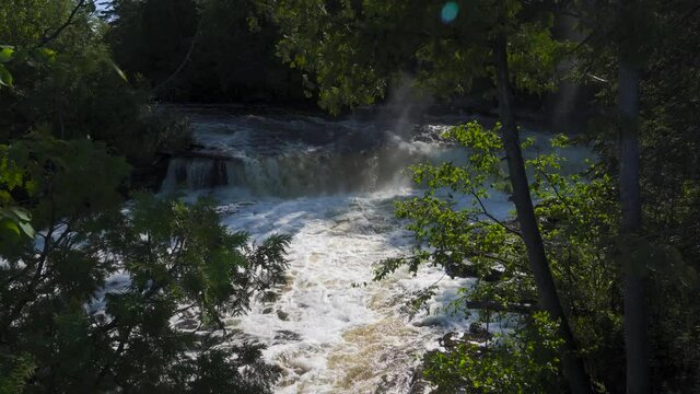 River from the Tahquamenon Falls in Upper Peninsula of Michigan; high angle long view of river between green trees, sunlight on the rushing water. 253

