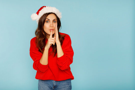 Young beautiful santa claus woman saying shh silence gesture over blue background copy space. Christmas and New Year secret concept.