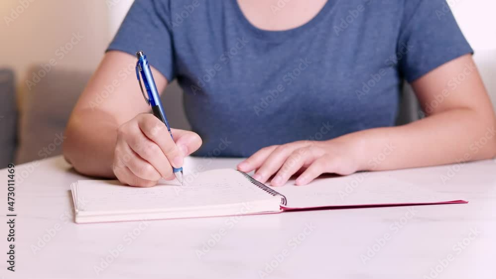 Aufkleber close up hands taking notes on a notebook about accounting of every month at home.