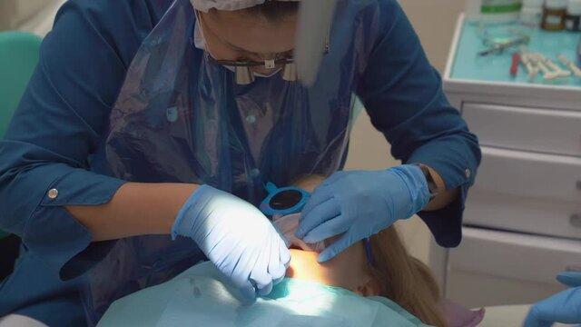 the doctor puts Mouth dilator in the mouth of a little girl's patient. 