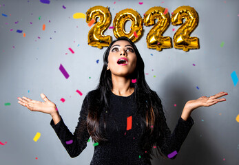 Portrait Of Beautiful Asian woman looking up on upcoming 2022 balloons, wearing shine black Dress Having Fun. new year concept on 2022.