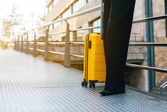 unrecognizable person next to yellow suitcase on the street. business trip concept.