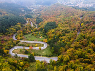 Stunning aerial view of road with curves crossing dense forest in autumn colors in Bulgaria. High...