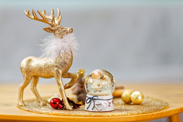Ein weihnachtlicher Hirsch als Dekoration neben einer Schneekugel