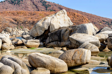 A group of granite boulders on the seashore at the foot of the mountain range.