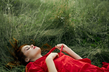 pretty woman in red dress lies on the grass in the field nature fresh air