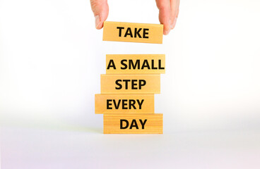 Take a small step every day symbol. Wooden blocks with words Take a small step every day. Beautiful white background, copy space. Businessman hand. Business, step every day concept.