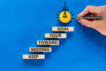 Keep moving toward your goal symbol. Wooden blocks with words Keep moving toward your goal. Light...