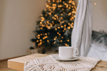 Cozy atmosphere with a cup of coffee on the background of the Christmas tree
