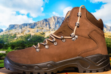 Brown hiking boots with defocused mountains background. 