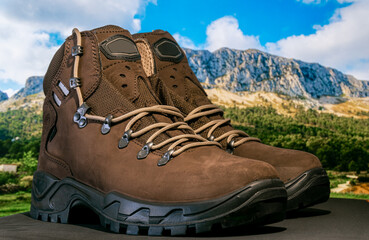 Brown hiking boots with defocused mountains background. 
