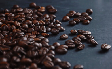 roasted brown coffee beans are scattered on the table. Close-up. Grains on a dark background. Coffee banner.