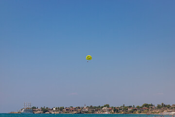 SIDE, TURKEY - AUGUST 21, 2021: Parasailing behind a speedboat on 115 metres in the air at the Mediterranean Sea.