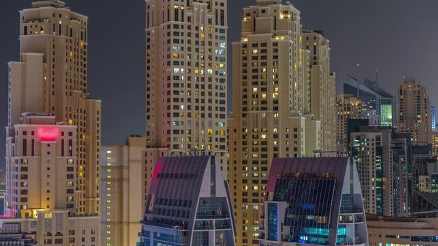Modern skyscrapers in Dubai Marina, close up view to many illuminated windows aerial night timelapse.