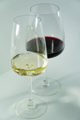 vasos de cristal sobre fondo blanco con reflejos, de vino blanco y vino tinto 