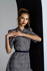 Beautiful, young girl in a gray strict dress, hair is gathered in a bun, portrait of a young girl