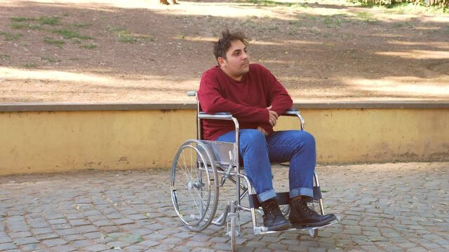 portrait of pensive young man with disability alone at park looking around