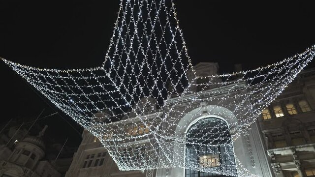 A big star-shaped Christmas decoration on a street sr night.
