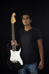 handsome young latin musician posing with his electric guitar with happiness on his face