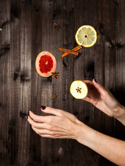 levitation of spices and fruits in women's hands on a dark wooden background