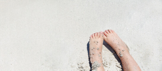 Childs feet lying on sandy beach barefoot closeup , summer banner panorama, mock up, copy space . Vacation with children concept.