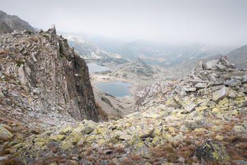 View of glacier lakes on Rila mountain through the rocky, pointy, mountain cliffs under a moody sky