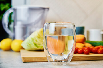 Glass of pure water, cleaning filter cartridge and fresh vegetables on table