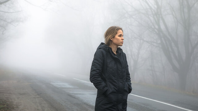 Fog landscape. woman walking  alone on scary foggy misty road.