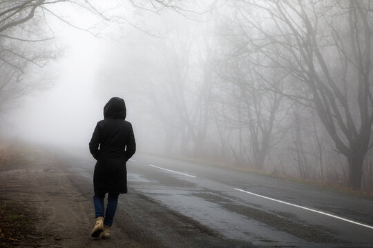 Fog landscape. woman walking  alone on scary foggy misty road.