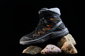 Black male boots on dark background. Stylish shoes for hiking on stones - obrazy, fototapety, plakaty