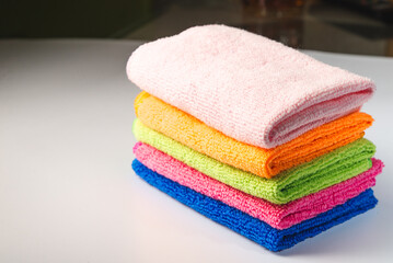 Obraz na płótnie Canvas stacked colorful microfiber cleaning cloths on a pink background. Colorful, dry microfiber cloths for different surfaces cleaning in kitchen, bathroom ,other rooms. Copy space for text or logo.
