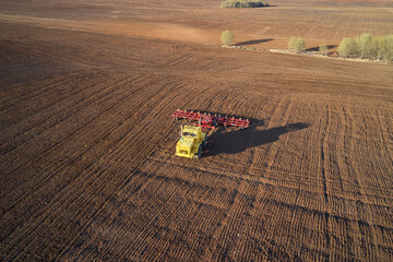 Pre-sowing tillage. A tractor with a trailed harrow is working in the field. Shooting from a drone.
