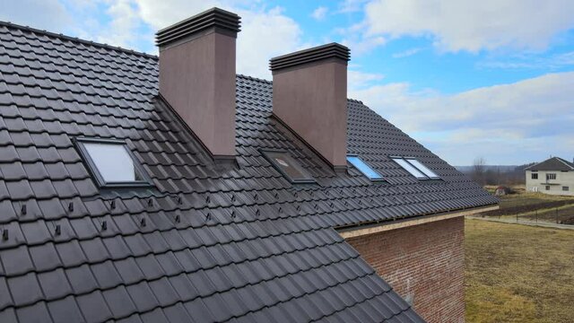 Aerial view of house roof top covered with ceramic shingles. Tiled covering of building under construction