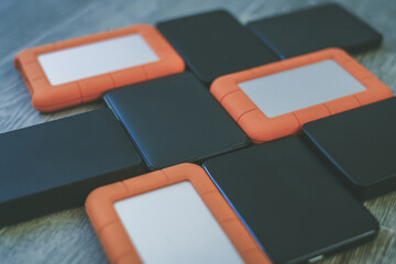 Many portable hard drives on the wooden floor. Mosaic of usb storage devices. External computer...