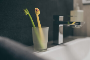 Closeup view of toothbrushes, sink, towels, and soap dispenser. Modern environment bathroom...