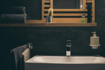 Closeup view of a sink with towels, toothbrush and soap dispenser. Modern environment bathroom fixtures with steel faucet. Cleanliness, health, recycling, pollution, cleaning, ethics, hygiene concept