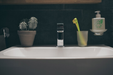 Closeup view of a sink with towels, toothbrush and soap dispenser. Modern environment bathroom...