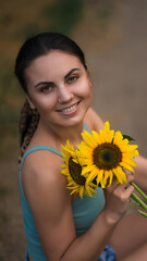 Portrait of a woman with sunflowers. The girl walks in the park with flowers. She is wearing denim shorts and a top. Leisure .