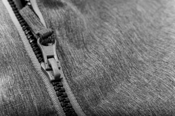 White lock with a zipper on gray clothes, jacket, jacket close-up. Lightning.